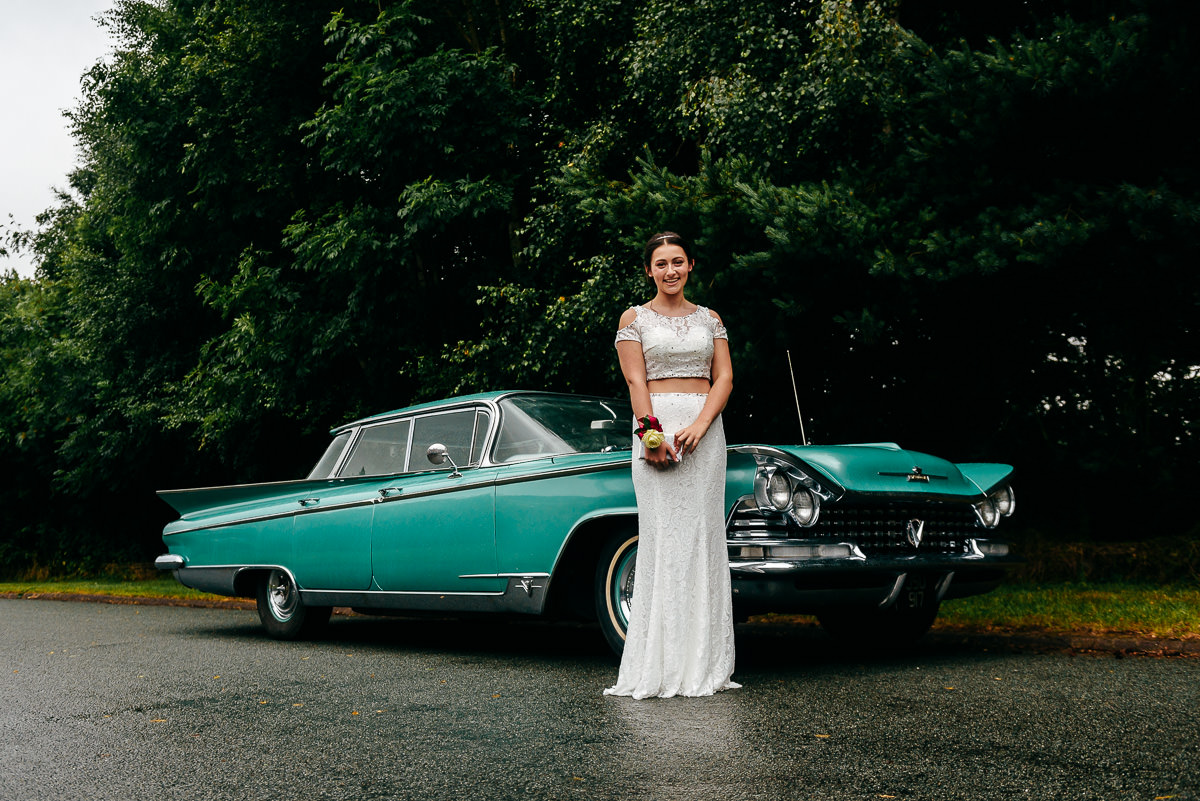 prom queen in front of a green Buick